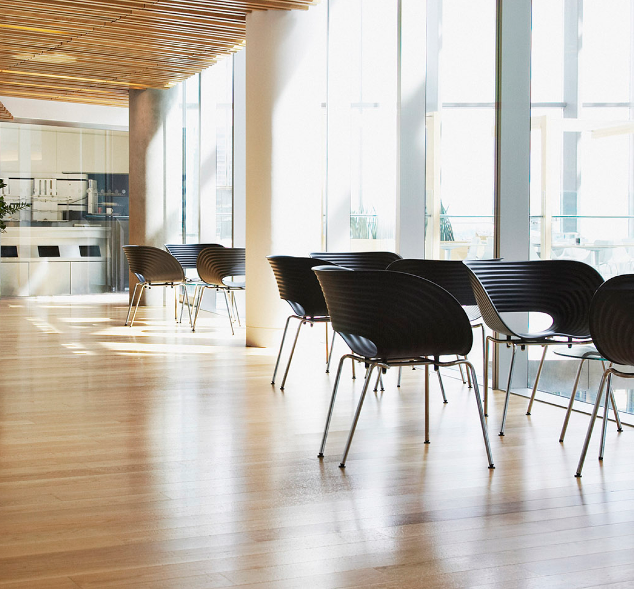 modern open office space with chairs and tables next to a large window
